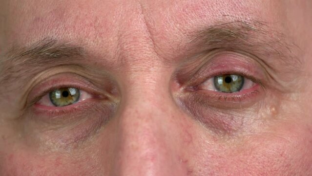 Close up of brown eyes of aged mature man. Serious or sorrow facial expression.