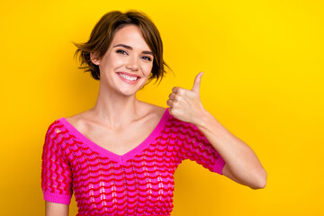 Portrait of smiling adorable youngster girl wear trendy pink knitted t-shirt thumb up recommend new summer event isolated on yellow color background