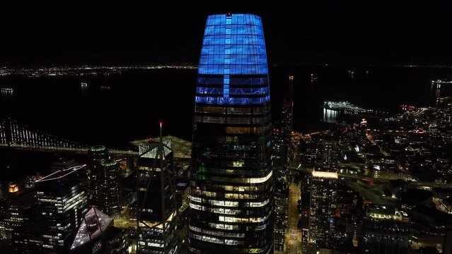 Circular footage of top section of Salesforce Tower at night. Modern high rise office building with blue illuminated top. San Francisco, California, USA