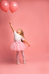 Obraz na płótnie Canvas little girl in a white t-shirt and a pink tutu with balloons on pink background. Ready to fly high