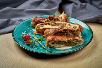 Chicken breast stuffed with mushrooms, baked in bacon on a blue plate