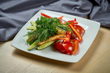 A plate with fresh vegetables, tomatoes, peppers and cucumbers.