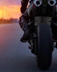 Naklejka premium Close-up of the rear wheel of a sportbike motorcycle, dual exhaust. Biker on a motorcycle at sunset