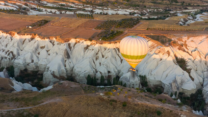 Hot air balloon flying over valley in Cappadocia, Turkey in sunrise sky, golden hour