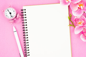 The blank open notebook and clock with pink color orchid for your text or message.