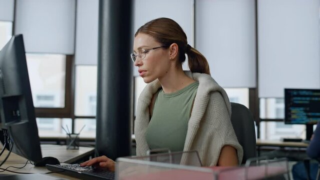 Software manager typing computer in office. Upset woman developer solve problem