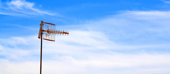 An antenna for receiving a radio station or TV programmes on a blue sky background.
