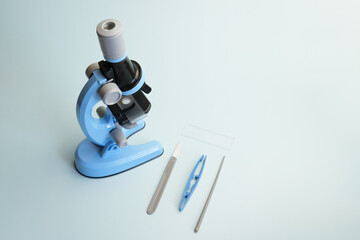 Children's toy microscope on a light blue background. An exact copy of a professional microscope with illumination and accessories for studying the world around. Template for inserting text