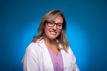 Fototapeta premium Photo of a sweet, confident mid-aged nurse dressed in a white coat and lilac blouse, with glasses looking at the camera.