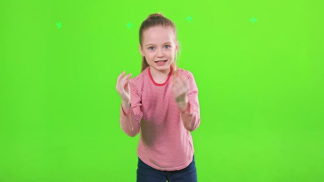Funny expressive female kid explaining to camera, gesturing actively. Front view of excited preteen girl telling something in motion, isolated on green background. Concept of gesturing, emotions.
