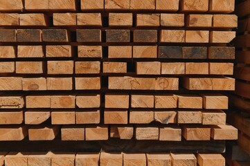 Fototapeta premium Stack of lumber of a wooden board from a tree, close-up, background. Wooden boards at the sawmill, carpentry workshop. Sawing and air drying of wood. Woodworking industry. Wooden boards