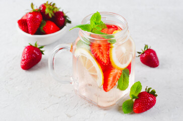 Strawberry Infused Water, Refreshing Cocktail, Lemonade, Detox Iced Drink with Fresh Strawberry, Lemon and Mint on Bright Background