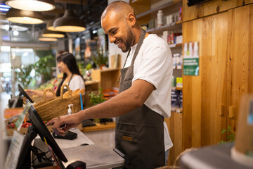 Focused black man using computer during work in store