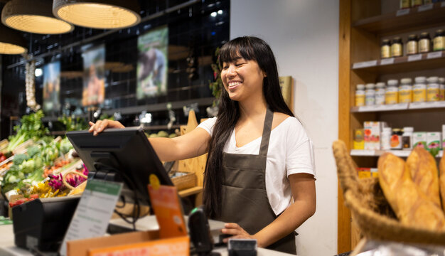 Cheerful Asian woman at counter with computer