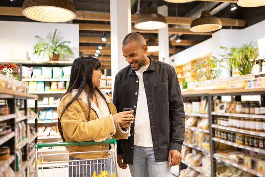 Happy diverse couple choosing food in supermarket