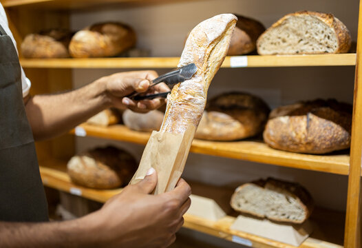 Unrecognizable black man putting bread in paper bag