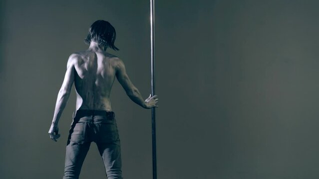 Strip dancer. Sexy man on pole dance. Pole dancer on pylon. Shirtless strong sexy man dancing. Male flexibility, and grace. Guy performing trick on pole. Male athlete doing acrobatic trick.