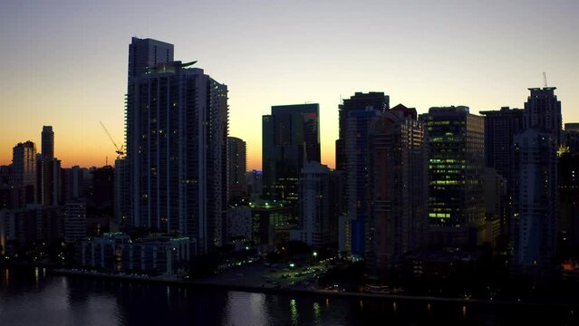 Aerial Shot Of Modern Buildings By Sea Against Sky At Dusk, Drone Ascending Over Coastline - Miami, Florida