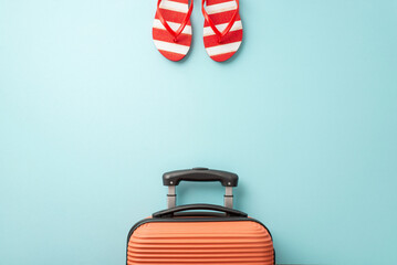 Let the vacation begin! Overhead view of an orange suitcase, red and white striped flip-flops on a...