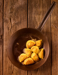 Ravioli in Pfanne angebraten auf rustikalem Holzfond