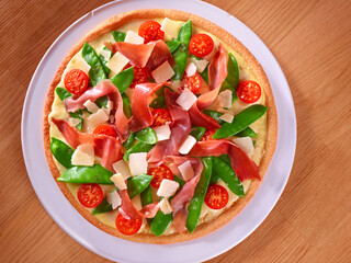 Pizza mit Zuckerschoten Raeucherschinken und Tomaten