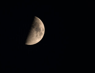 Księżyc na nocnym niebie w pierwszej kwadrze.