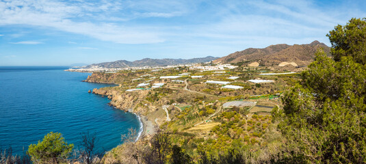 View on Maro beach and Nerja in the back, located on the coastline of the Costa del Sol in Southern Spain; plastic greenhouses dotted all over the area