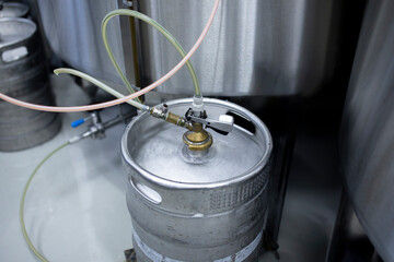 worker refilling the metal keg with beer, warehouse on the brewery production