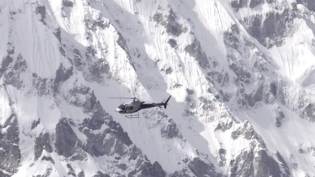 Rescue helicopter flying with dramatic snow covered cliffs 
Himalaya Mountain, Nepal 2023
