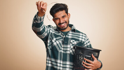 Indian bearded man taking off throwing out glasses into bin after medical vision laser treatment...