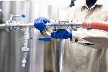 male worker on the factory repair the pipe and hose joint, drink production equipment