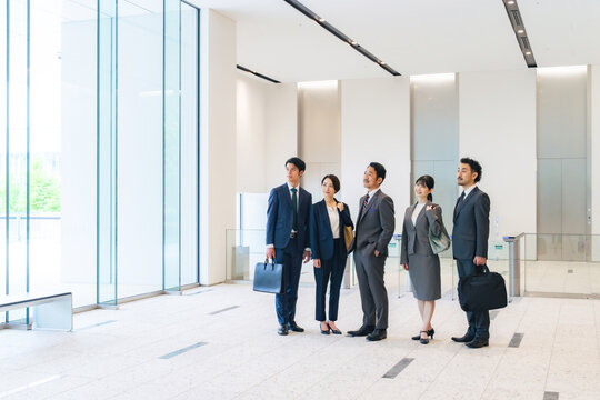 オフィスビルのロビーで空を見上げるビジネスパーソンのグループ