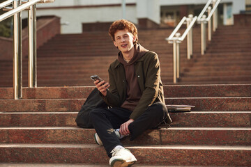 Young student with curly hair is outdoors near university