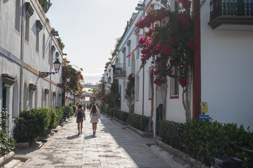 Detail of the beautiful picturesque streets of the fishing village of Mogan, two girls stroll at sunset