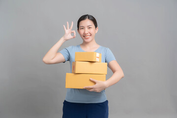 Young Asian businesswoman holding parcel box on gray background in studio. The idea of ​​doing a small SME online sales business