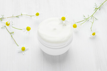 Fototapeta na wymiar White nourishing cream with chamomile in a white jar.