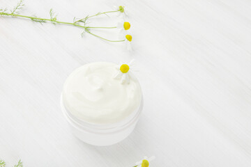 Fototapeta na wymiar White nourishing cream with chamomile in a white jar.