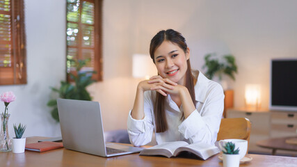 Relaxing time concept, Woman reading book with smile happiness after working at modern home office