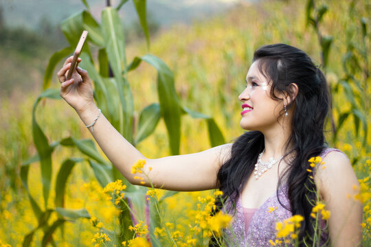 Foto de mujer hablando selfie en celular mientras camina en campo ,bosque,amarillos ,flores,atractiva
