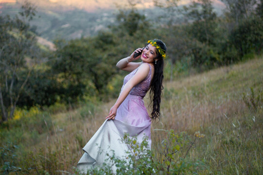 Foto de una mujer agradable hablando por celular mientras camina en un campo ,flores corona,