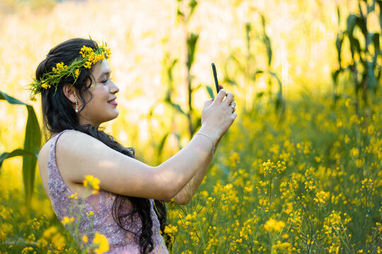 Foto de mujer hablando selfie en celular mientras camina en campo ,bosque,amarillos ,flores,atractiva