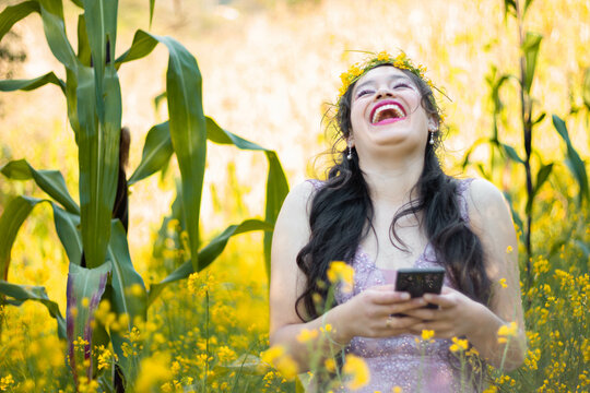 Foto de una mujer con una carcajada agradable por celular mientras camina en un campo ,fondo naturaleza,bosque,mujer bonita con telefono