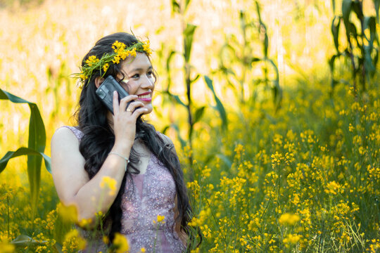 Foto de una mujer agradable hablando por celular mientras camina en un campo de flores amarillo,fondo naturaleza,bosque,mujer bonita con telefono