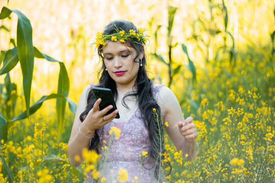 
Foto de una mujer sosteniendo un tel&eacute;fono celular en la mano en el campo, una linda chica mirando la pantalla del m&oacute;vil,