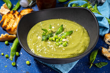 Homemade green pea cream soup, green gazpacho cold soup with peas decor and croutons, tasty vegan food, diet dinner recipe