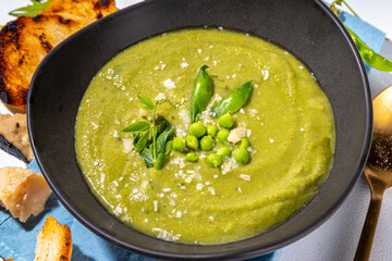 Homemade green pea cream soup, green gazpacho cold soup with peas decor and croutons, tasty vegan food, diet dinner recipe