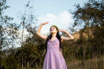 una mujer hermosa con un vestido ligero en un campo  con las manos levantadas sobre su cabeza en...