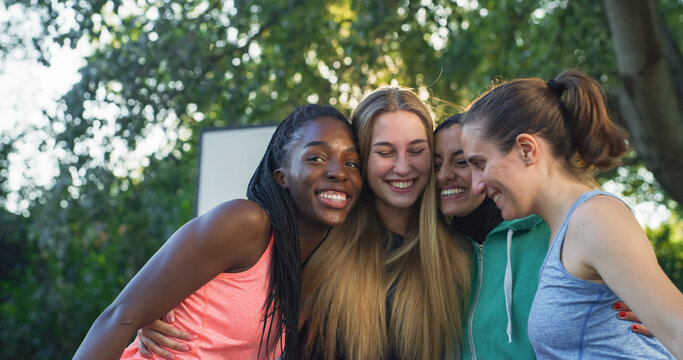 Portrait of Multiethnic Female Friends in Sports Clothes Hugging and Laughing. Group of Young Women Celebrating a Win in Outdoor Basketball Court Together, Showing Affection and Solidarity