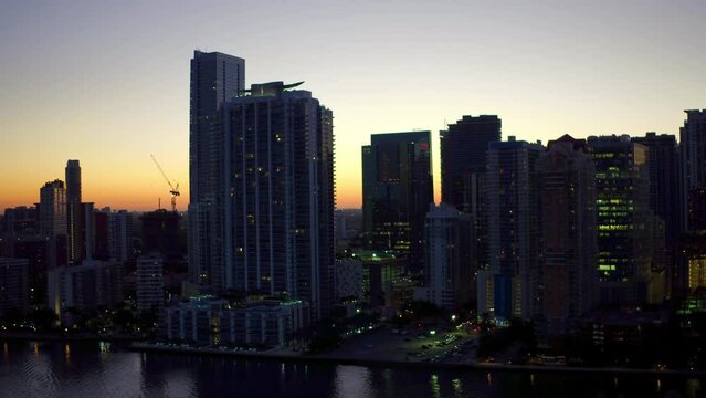Aerial Panning Shot Of Modern Buildings In City By Sea Against Sky, Drone Flying Over Coastline At Dusk - Miami, Florida