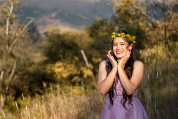 Foto de hermosa mujer feliz sonriendo y caminando en el campo con una corona en la cabeza de...